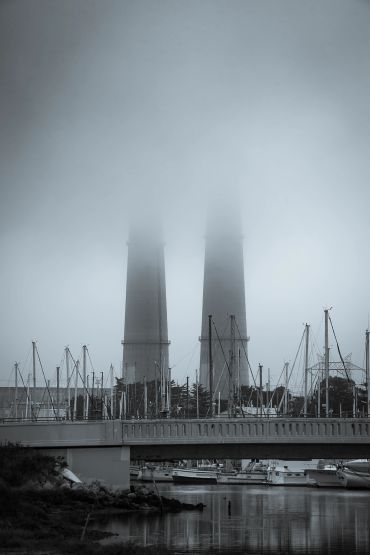 Foggy scene with two tall stacks and boats.