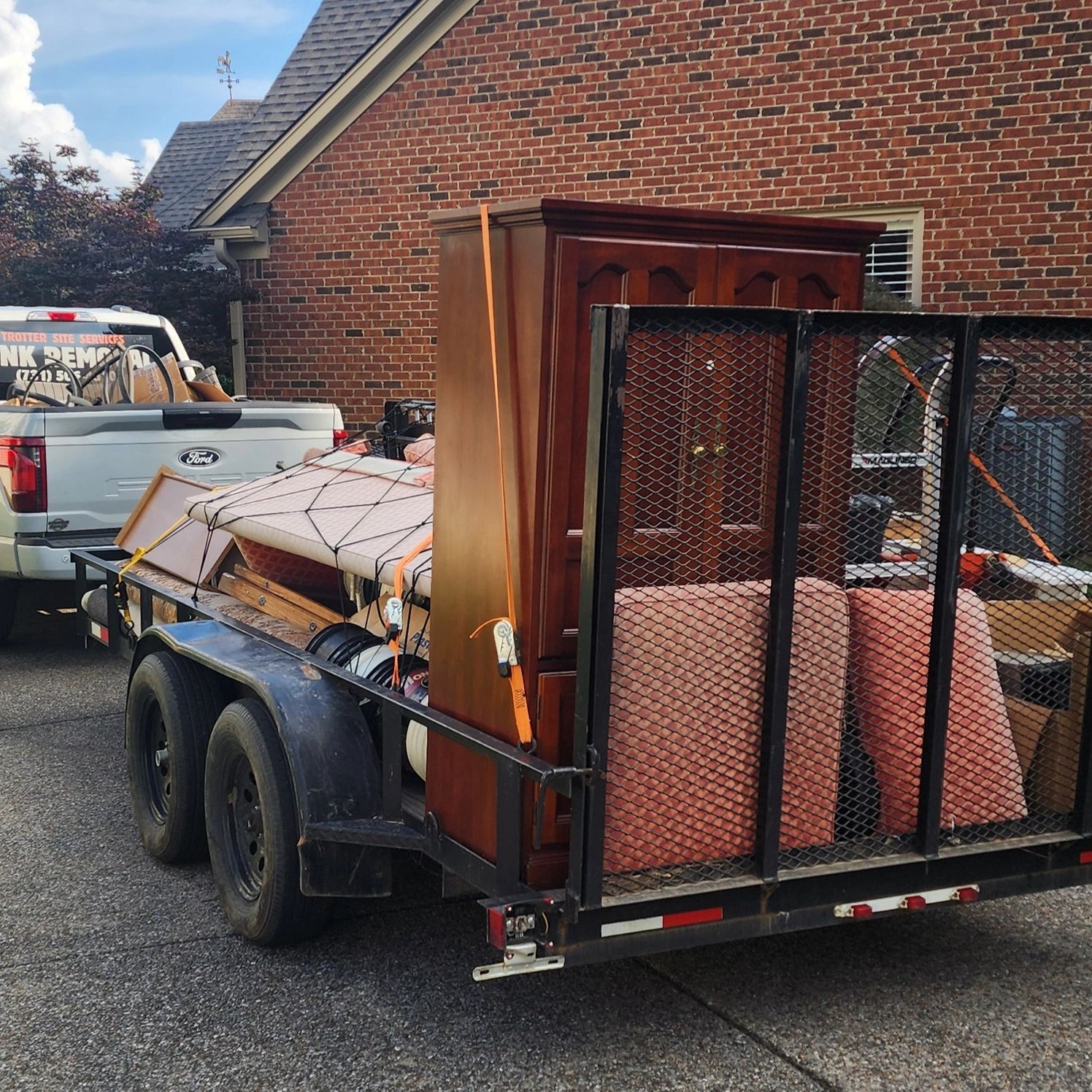 A trailer loaded with furniture and other items attached to a white Ford truck.