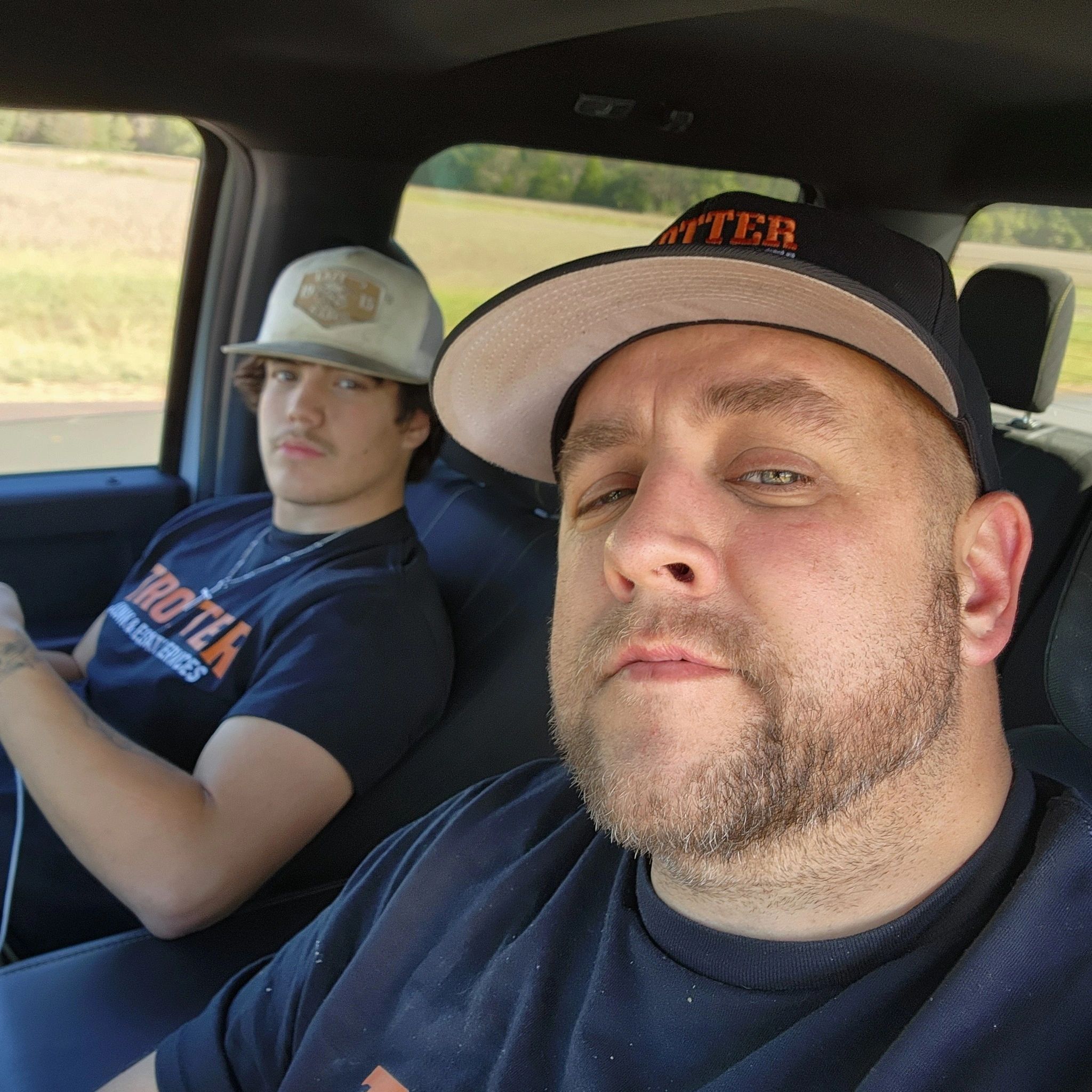 Two men wearing hats in a car.
