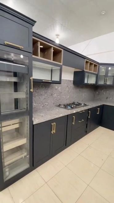 Modern kitchen with black cabinets, gold handles, and a marble countertop.
