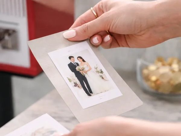 Person holding a printed wedding photo of a bride and groom.