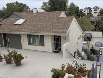Residential house with potted plants and driveway.