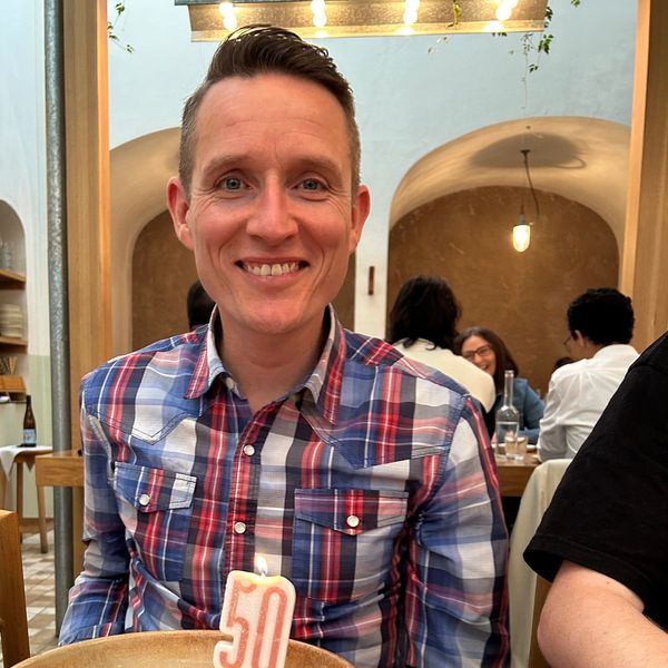 Man smiling with a birthday cake and a '50' candle.