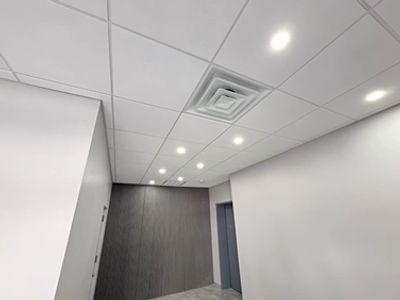Modern ceiling with recessed lights and ventilation in a clean office space.
