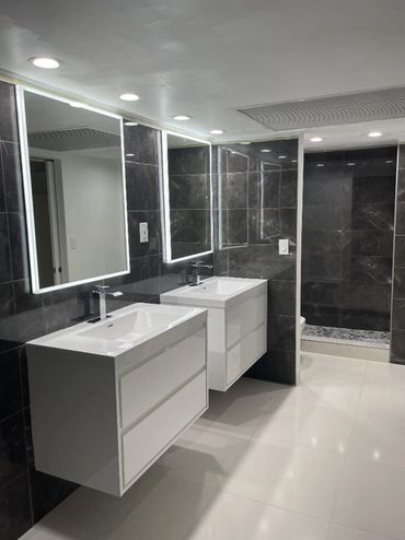 Modern bathroom with dual sinks and illuminated mirrors.