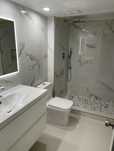 Modern minimalist bathroom with marble walls and pebble shower floor.