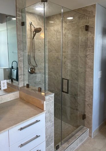Modern bathroom with glass shower enclosure and beige tiles.
