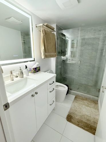 Modern bathroom with white cabinetry and glass shower enclosure.