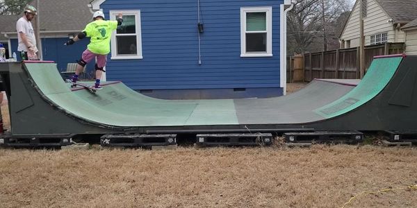 Person skateboarding on a small backyard half-pipe ramp.
