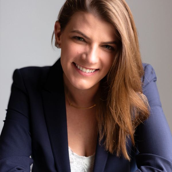 Smiling woman in navy blazer with brown hair.