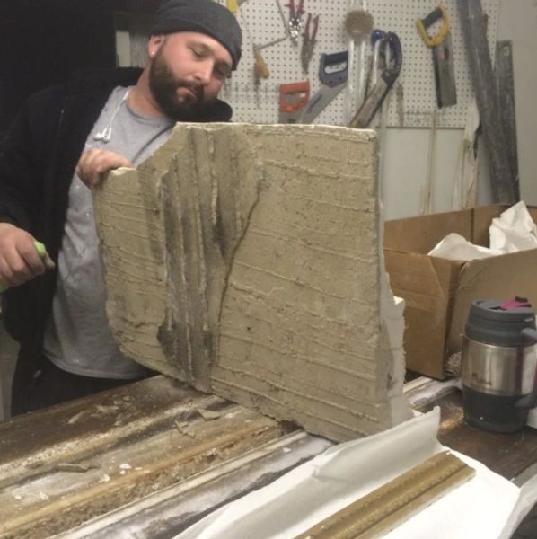Man inspecting a large concrete slab in a workshop.