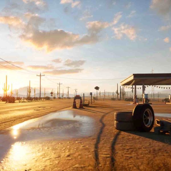 Desert road at sunset with gas station and scattered tires.