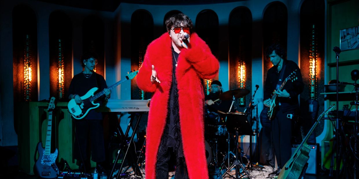 Singer in red coat performing with band.