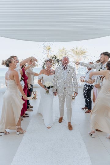 Newlyweds walk down the aisle as guests shower them with confetti.