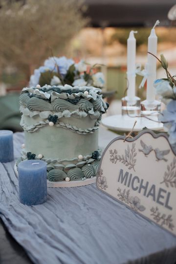 Elegant blue-themed cake and candles on a table with a sign reading "Michael".