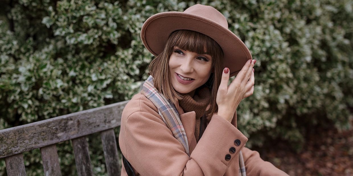A smiling woman wearing fashionable autumn clothes and a hat while best Cyprus brand photographer 