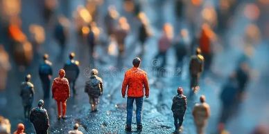 Miniature people figures walking, one in red jacket stands out.