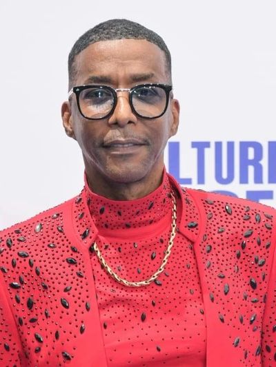 Man wearing glasses and a red embellished outfit.