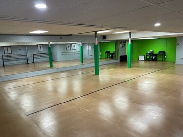 Spacious dance studio with mirrored walls and green accents.