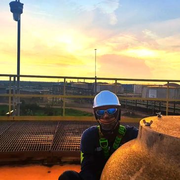 Técnico industrial realizando mantenimiento de válvula en campo al atardecer, con EPP completo.