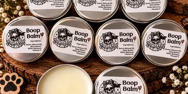 Tins of Boop Balm arranged on wooden surface.