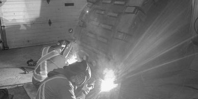 Two welders repairing large equipment bucket 