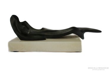 Silueta de una mujer recostada, en bronce.