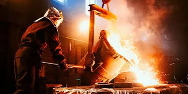 Trabajador vertiendo metal fundido en una fundición.