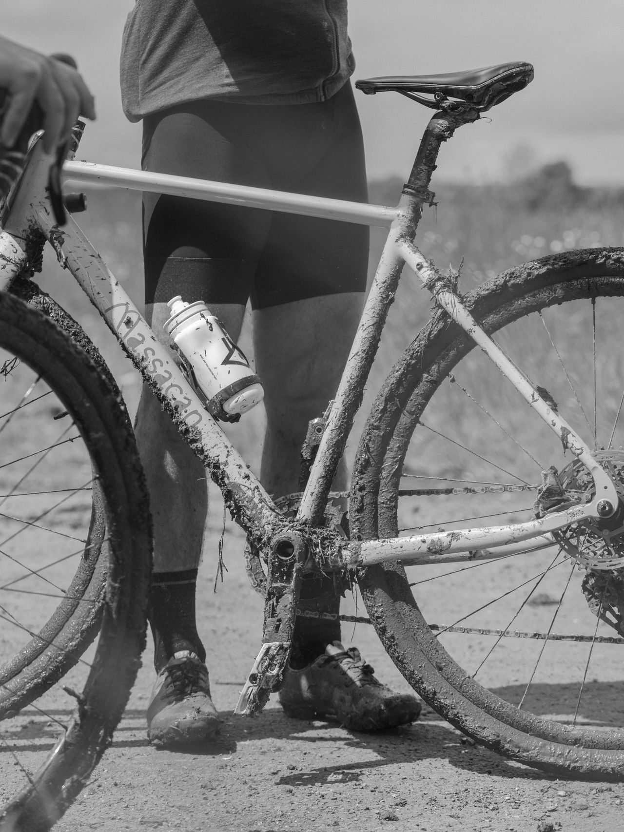 Cyclists with muddy bikes after a ride on a dirt path.