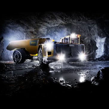 Heavy mining truck illuminated inside a dark underground tunnel.