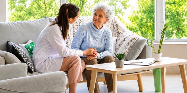 Caregiver comforting elderly woman at home.