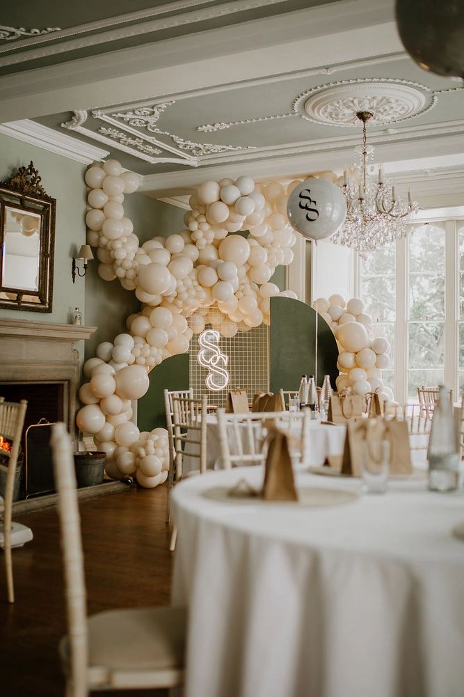 Elegant event setup with cream balloons and chandeliers in a classic room. Manor House display for corporate events. 