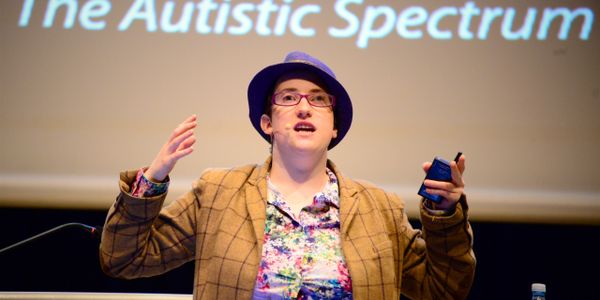 `photo of Robyn wearing-a. purple-hat giving a lecture. 