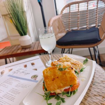A gourmet sandwich with greens and a glass of water on a table.
