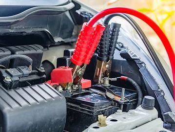 Car battery being jump-started with jumper cables.