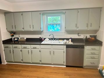 Clean kitchen with white cabinets and dark countertop.