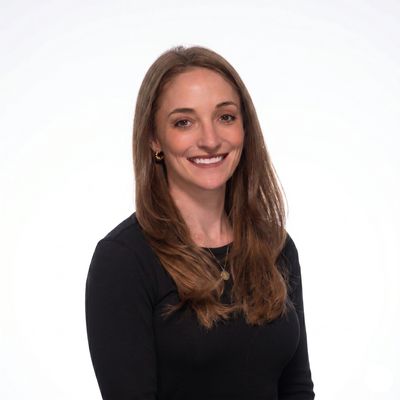 Smiling woman with long brown hair and black top.