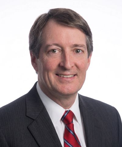 Portrait of a middle-aged man in a suit with a red striped tie.