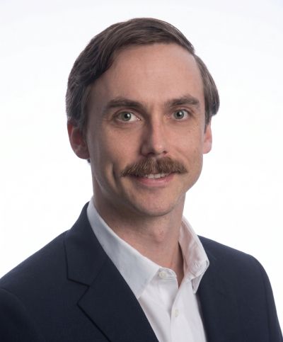 Man with mustache in a suit jacket and white shirt.