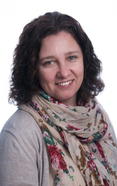 Woman with curly hair wearing a floral scarf.