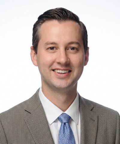 Professional headshot of a smiling man in a suit and tie.