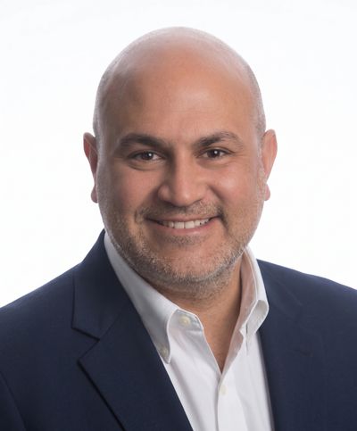 Smiling bald man in a suit jacket and white shirt.