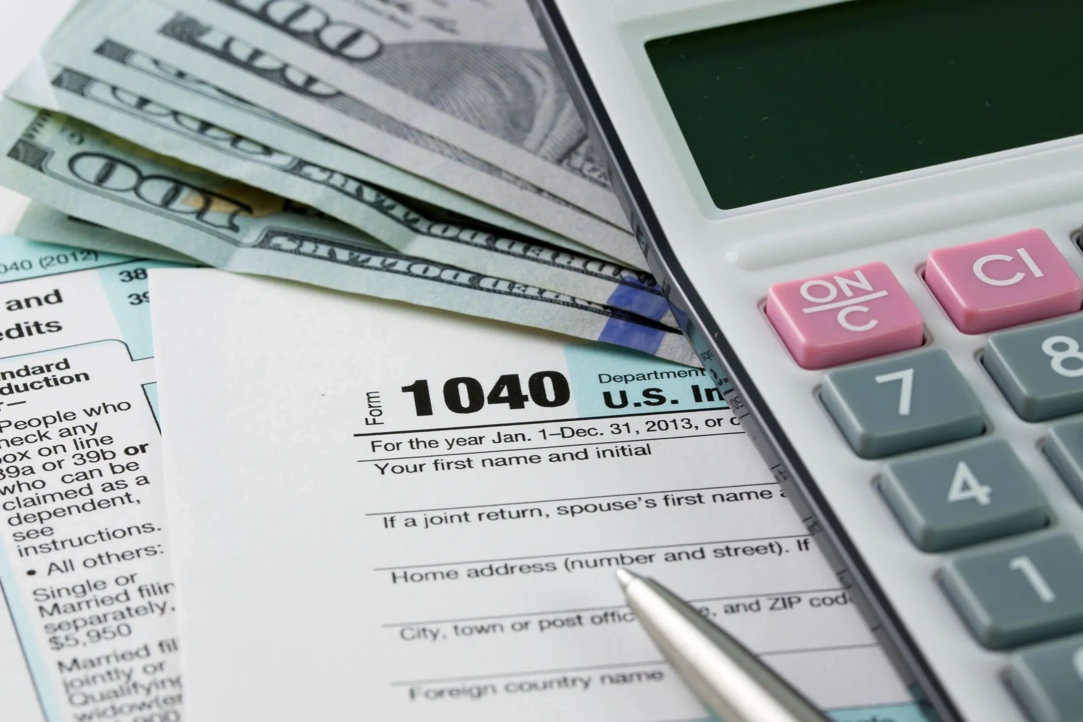Tax form 1040 with cash and calculator for financial calculations.