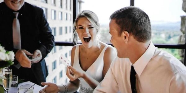 A woman excitedly reacts to a card trick at a celebration.