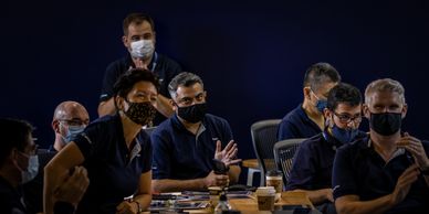 Group of masked people in a dark room.