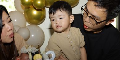 A family celebrating a toddler's second birthday with balloons and cake.