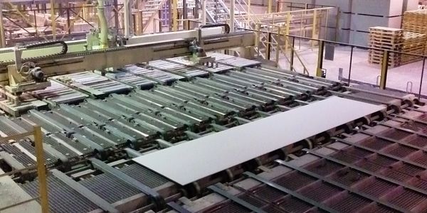 Automated industrial machinery handling large flat panels in a factory.
