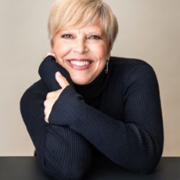 Smiling woman with short blonde hair in black sweater.