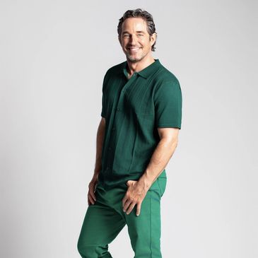Smiling man in green outfit.