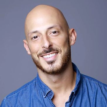 Smiling bald man with beard wearing a blue shirt.